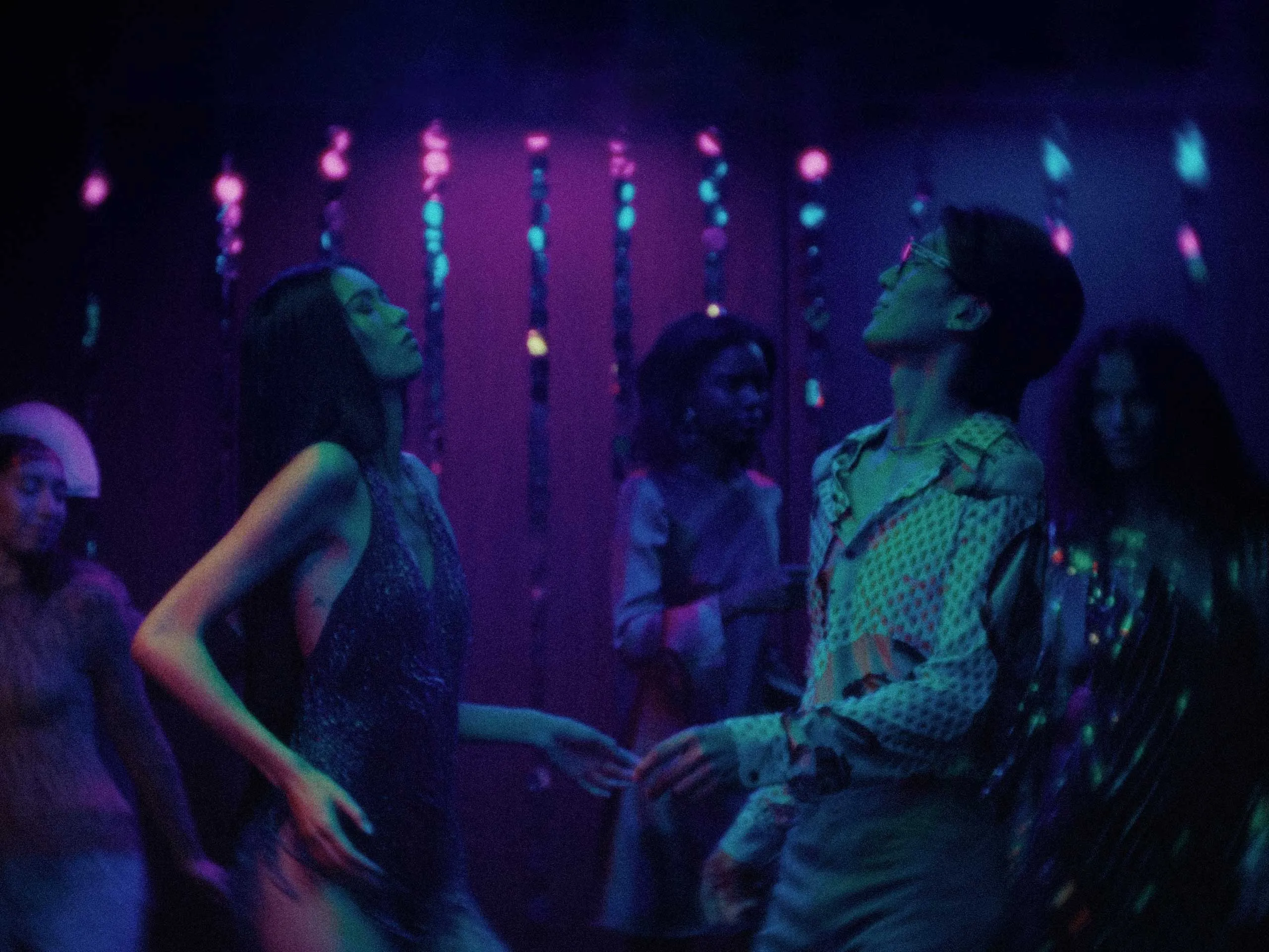 People dancing in a dark club with purple and blue neon lighting.