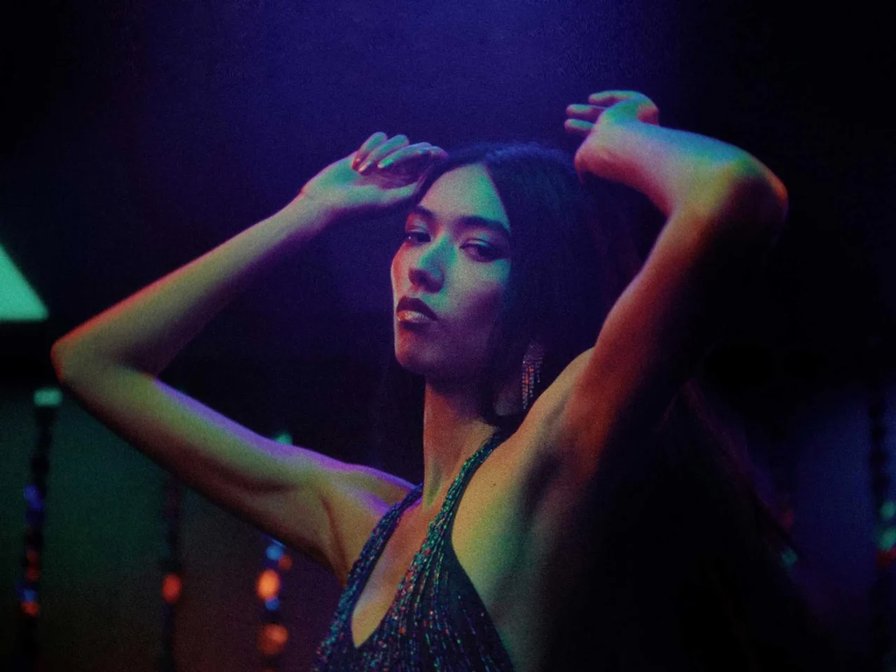 Dancers in a dark club under purple-blue neon lights, facing each other as they move to the music.