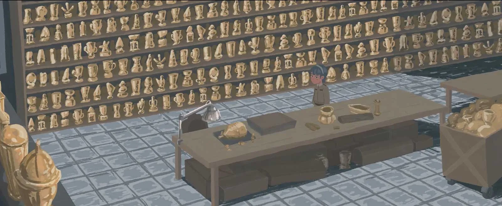 A person stands behind a worktable in a shop lined with shelves of gold figurines and trophies.