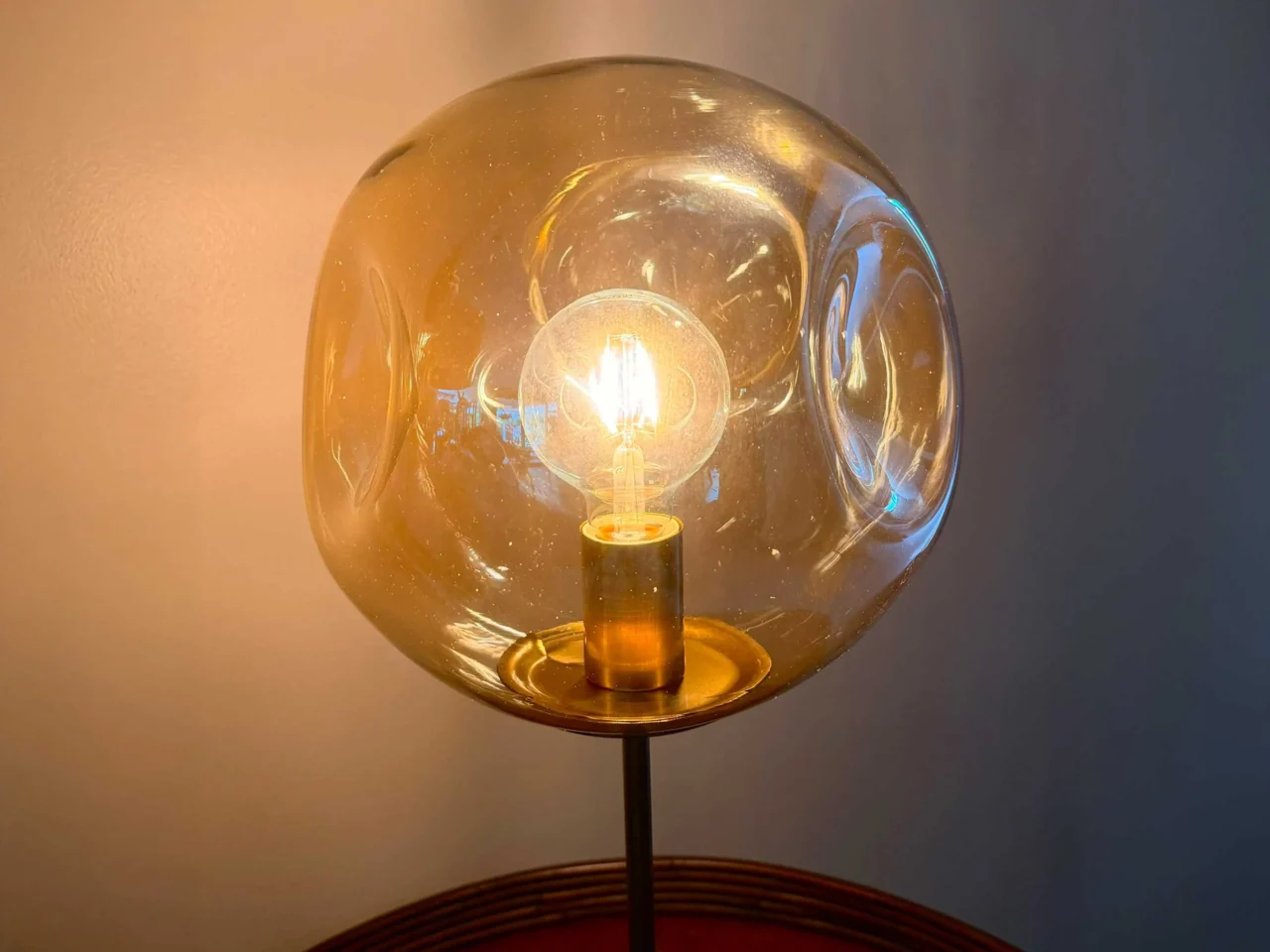 Two glass globe lamps with warm light against a neutral wall.