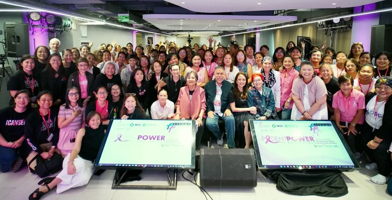 Large diverse group posing for a group photo at an indoor event; two screens in front display 'POWER' with ribbons logo.