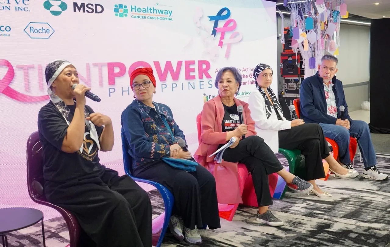 Five panelists seated in colorful chairs on a stage, each holding a microphone during a health event discussion, with sponsor logos in the background.