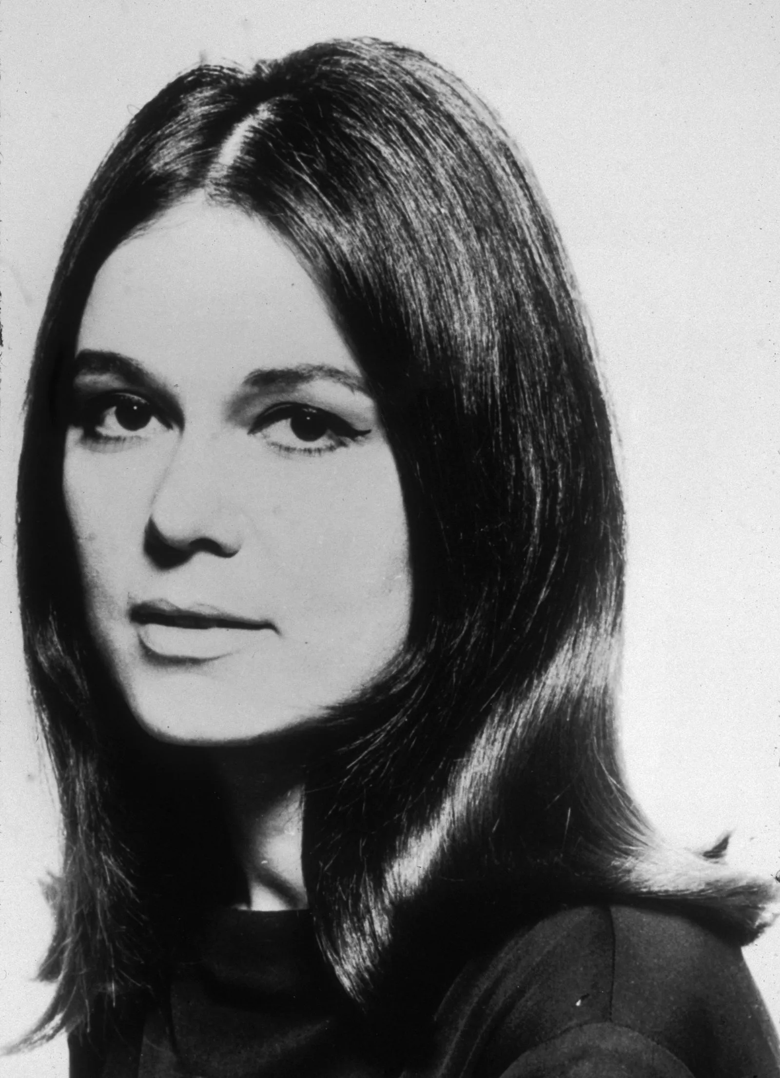 Close-up black-and-white portrait of a young woman with straight, shoulder-length hair and a dark turtleneck/sweater.