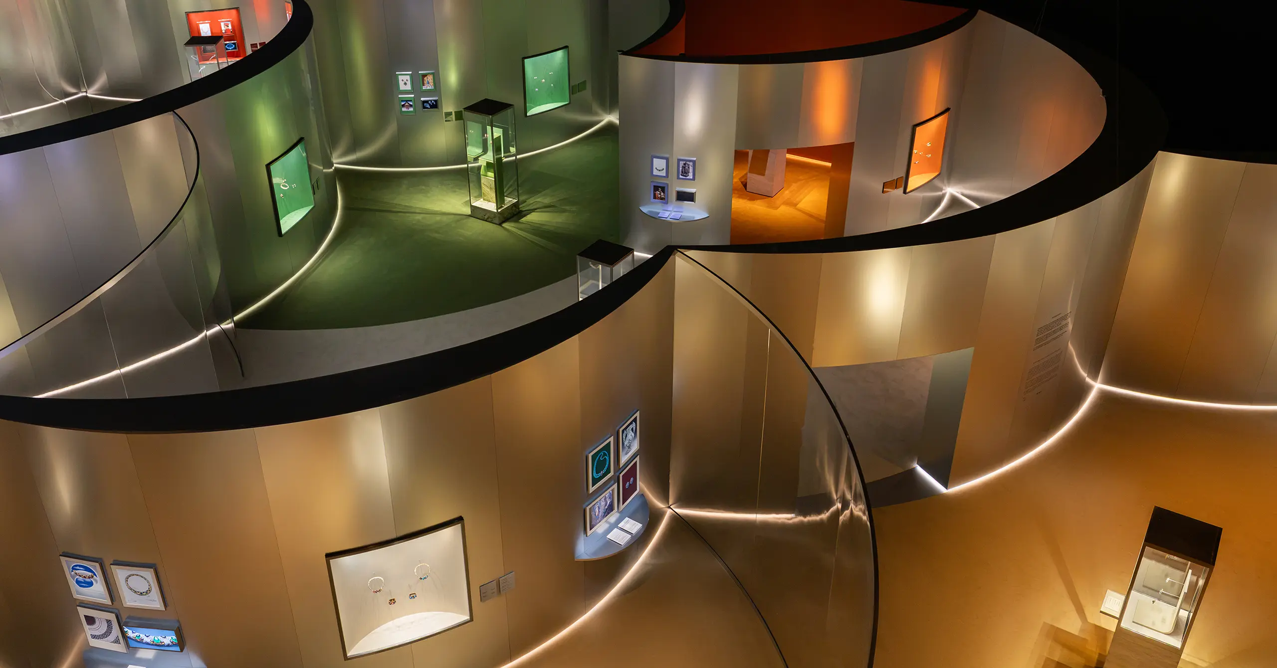 Interior of a circular museum/gallery with curved beige walls and a winding walkway, displaying glass cases and framed artworks.