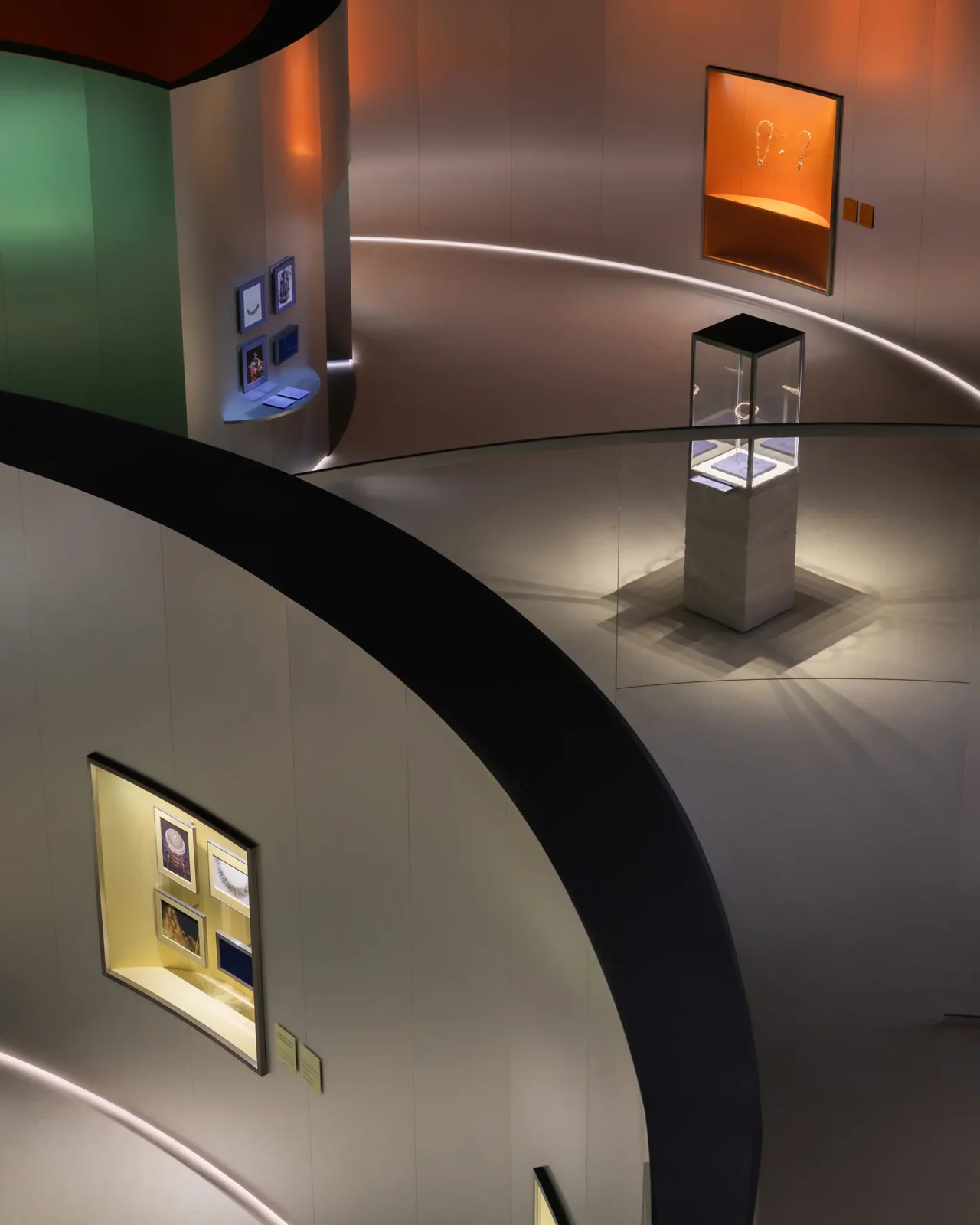 Interior of a circular museum/gallery with curved beige walls and a winding walkway, displaying glass cases and framed artworks.