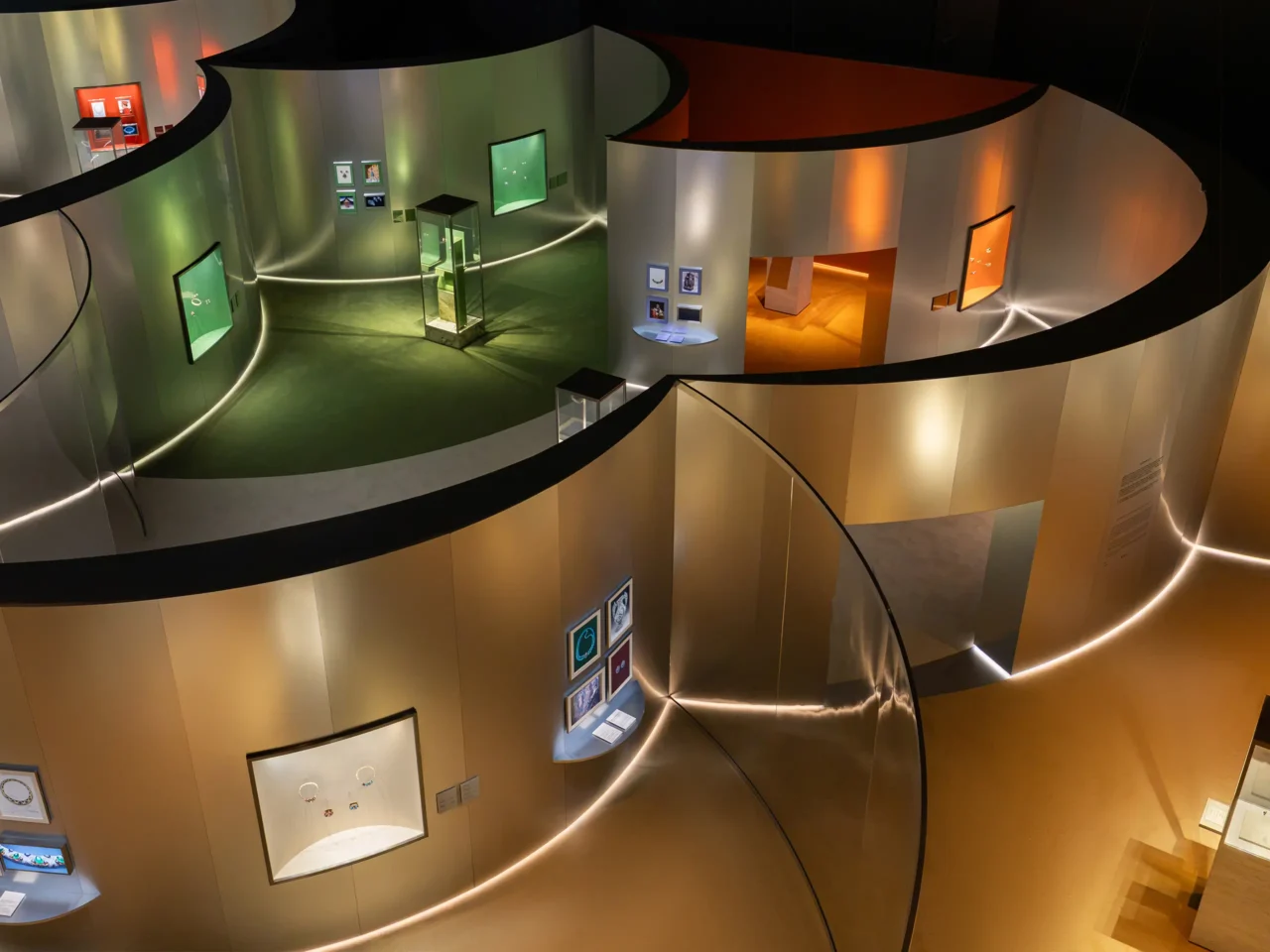 Interior of a circular museum/gallery with curved beige walls and a winding walkway, displaying glass cases and framed artworks.