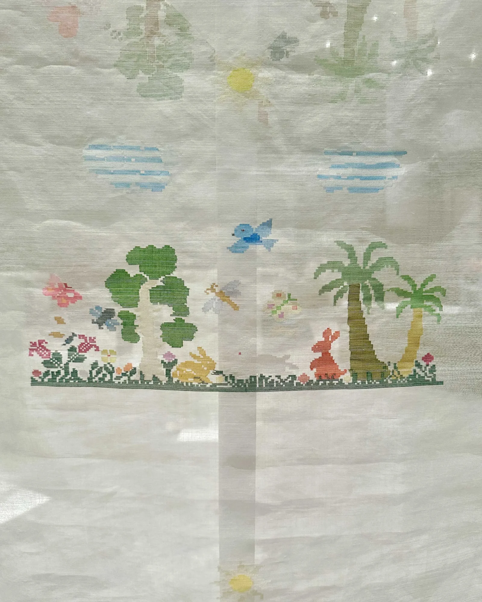 Light-colored fabric with a subtle tropical floral print, including green leaves, pink flowers, and palm trees against a pale background.