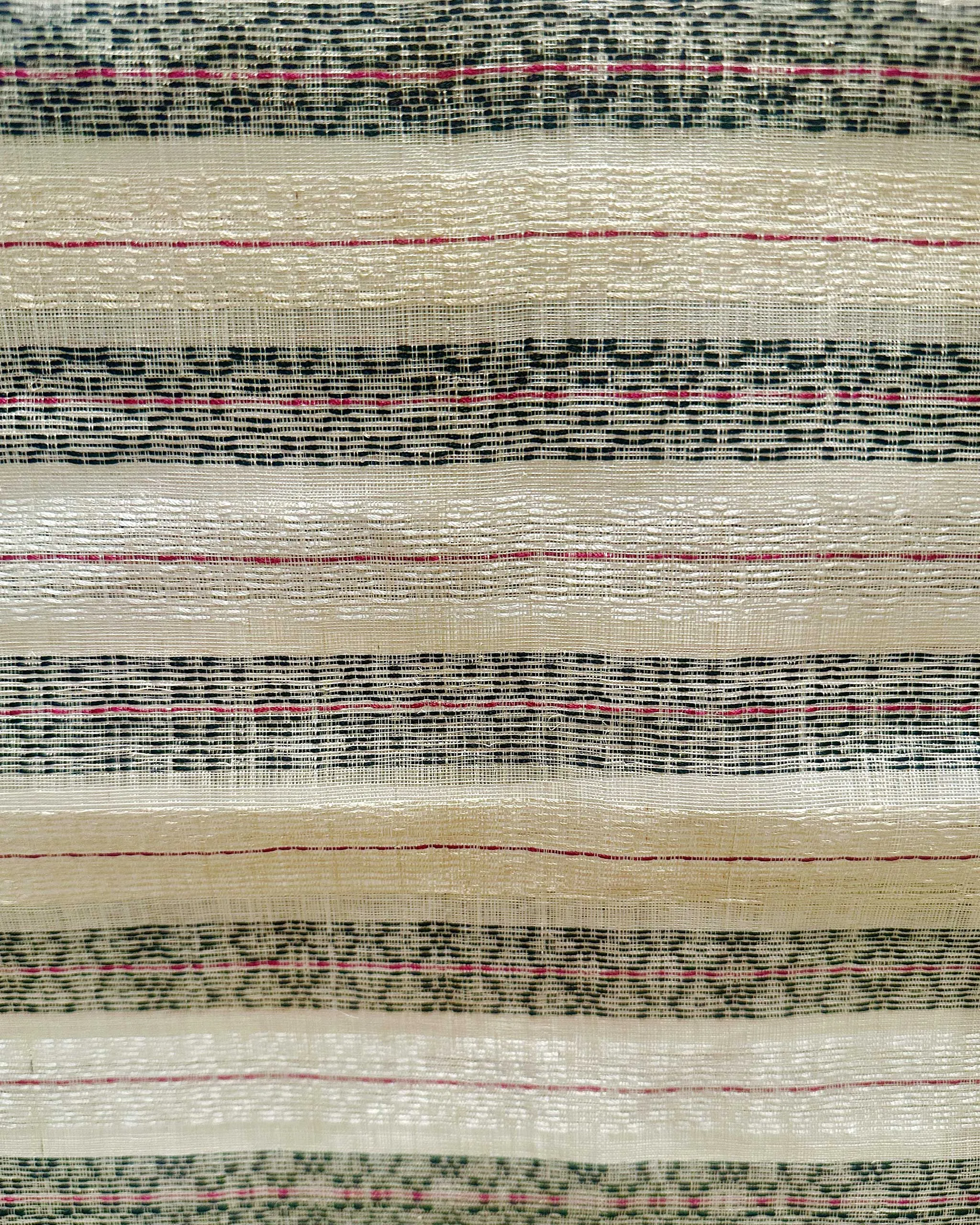 Close-up of woven textile with alternating wide beige bands and dark blue/black stripes accented by thin pink lines