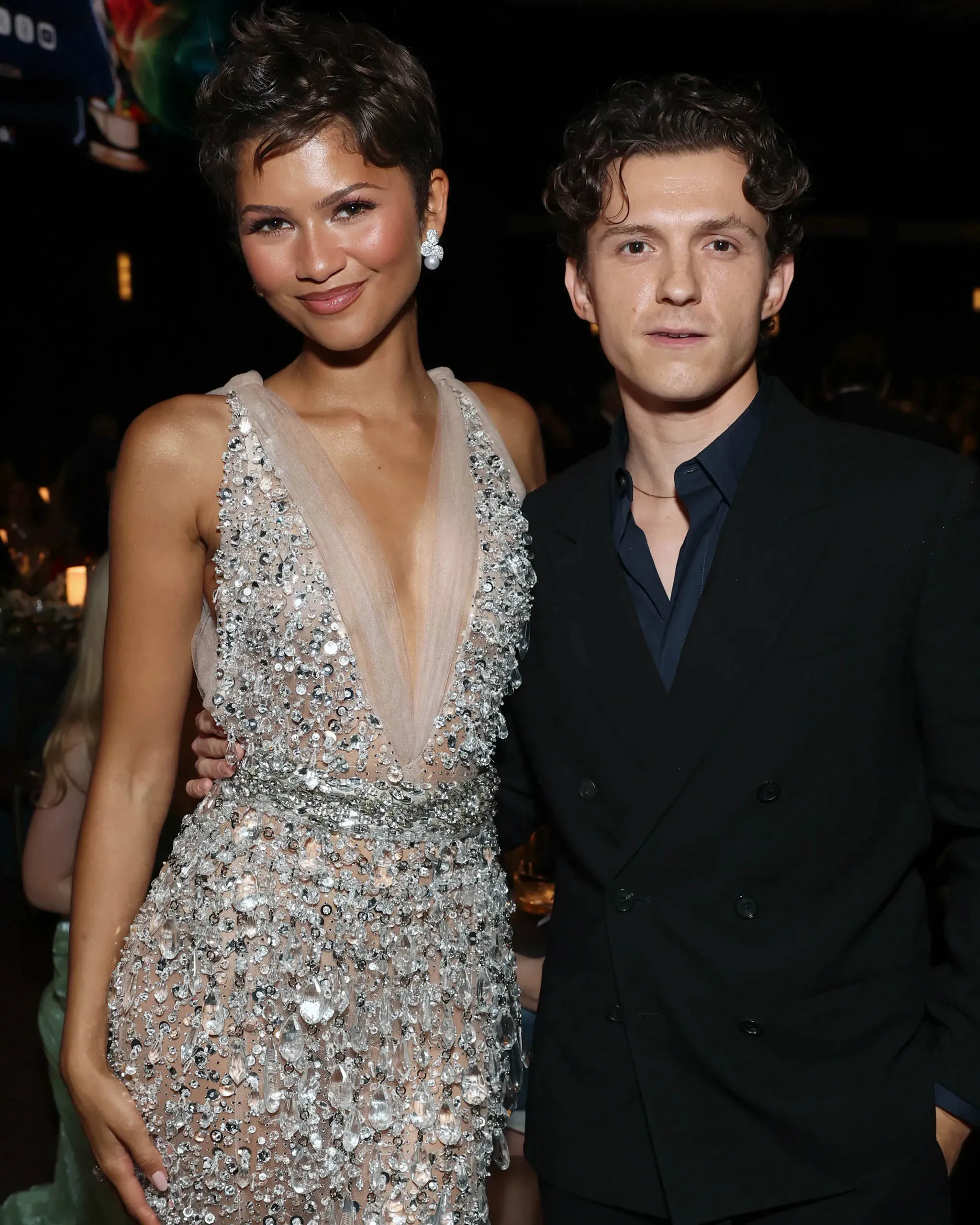 Rihanna in a sparkling beaded gown posing with a man in a dark suit at a formal event.