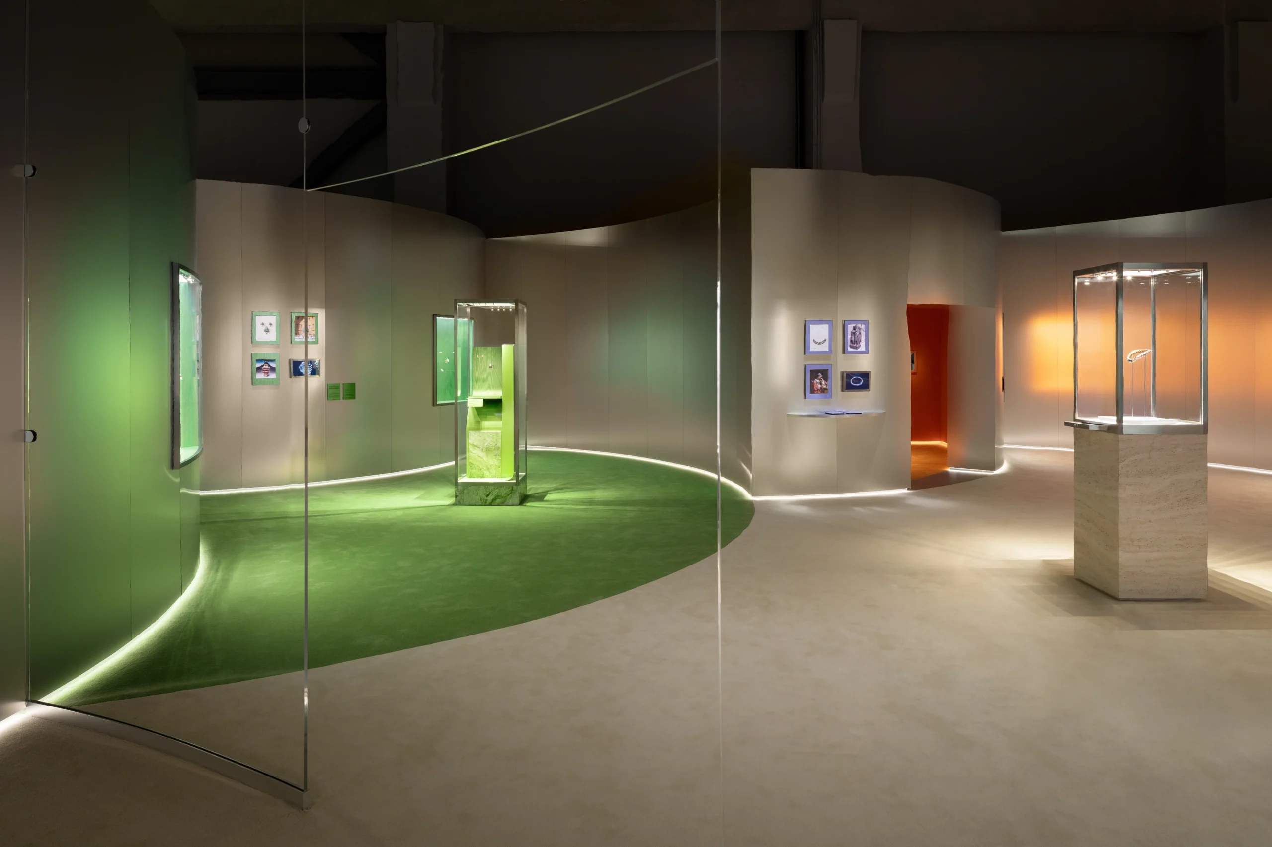 Museum interior with curved white walls, glass display cases, and a green-lit circular floor area.