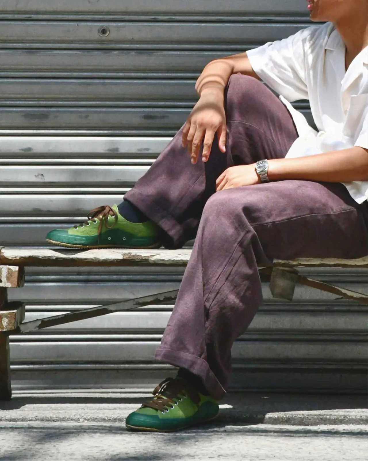 White sneaker with tan sole stepping on rocky surface, denim jeans visible at the ankle.